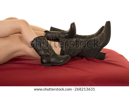 a woman and her child laying together with their cowboy boots on their feet.
