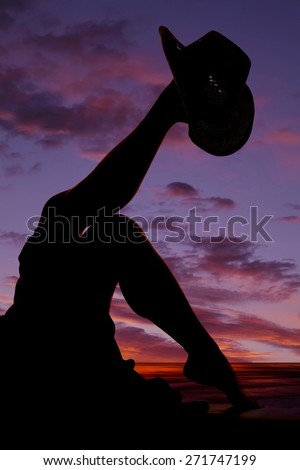 a silhouette of a woman with a cowboy hat on her foot.