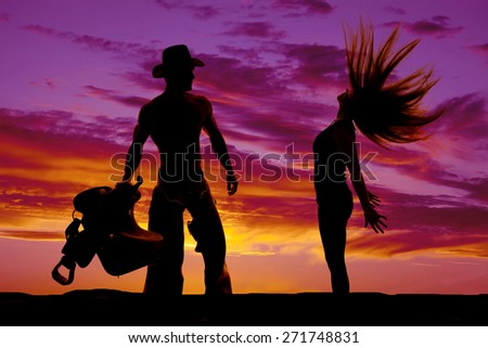 a silhouette of a woman flipping her hair back, with her cowboy near by.