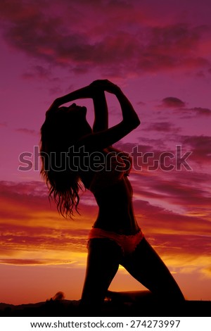 a silhouette of a woman in her bikini leaning back.