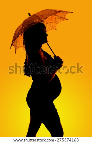 a silhouette of a woman under her umbrella with her belly showing.
