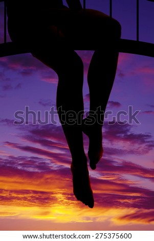 a silhouette of a woman\'s legs hanging down from a bridge.