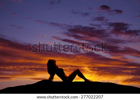 A silhouette of a woman sitting with the sun glow on her skin.
