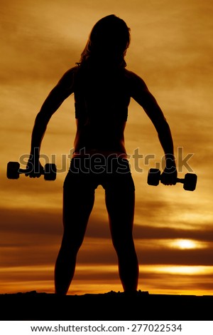A silhouette of the back of a woman working out with her weights.