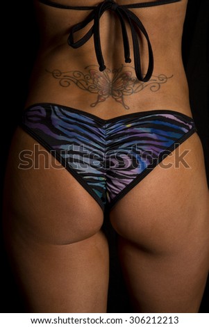 A close up of a woman in her bikini bottom with a tattoo on her lower back.