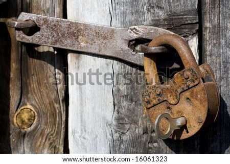 Old opened rusty and dirty metal lock with key on a old wood door