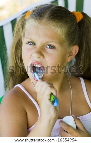 little blond girl cleaning teeth by toothbrush