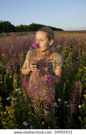 young blonde woman on summer meadow at sunset time