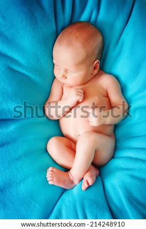 newborn baby lying on his back on a blue blanket
