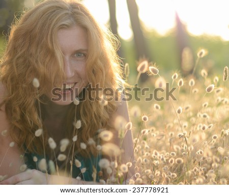 Portrait of a red-haired beautiful happy woman in the bunny tail grass
