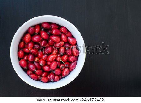 Closeup of rosehip berries in white bow, black background, horizontal