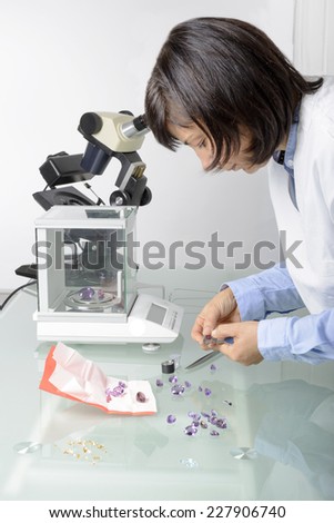 Woman, appraiser gems in laboratory with microscope and gemology instruments