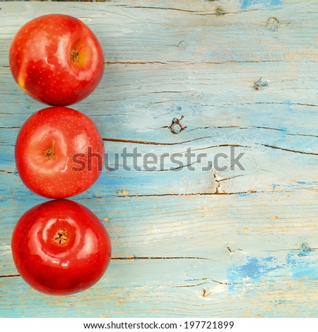 Rustic background three red apples on old blue wooden background