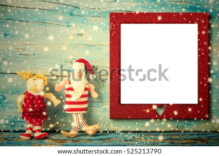 Christmas photo frame card, Santa Claus and reindeer rag dolls and empty photo frame with heart , vintage tone wooden background