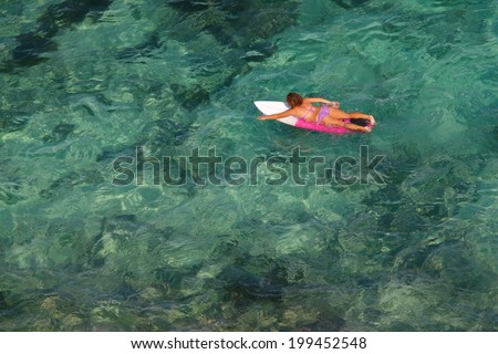 Young woman floating on a surfboard in the ocean