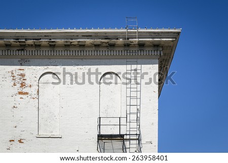 Top Corner of an Old White Building with a Fire Escape
