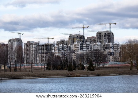 Construction of high-rise buildings with cranes on river bank
