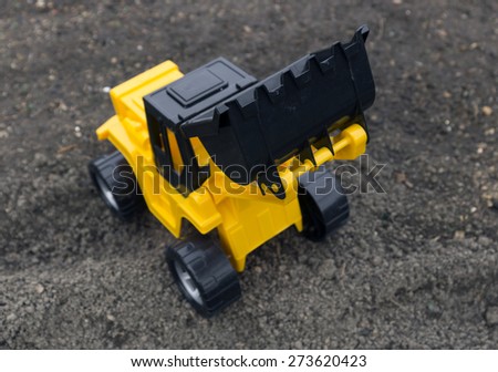 Children\'s toys excavator with a blade on the field