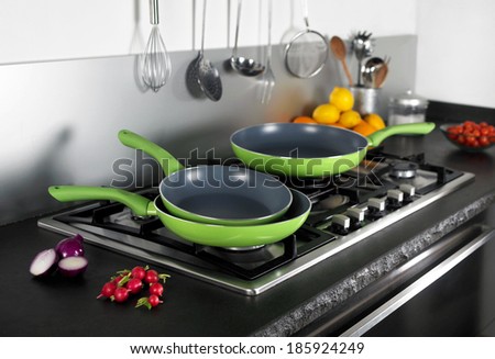 elegante modern cooking place with green frying pans, some food stuff and kitchen tools