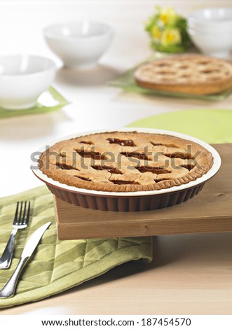 silicone pie moud on wooden surface with pies, linen and cutlery on table.
