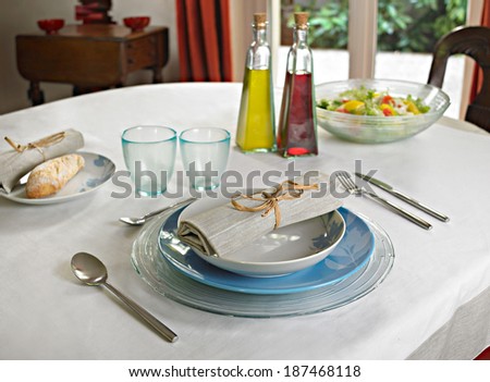 nice and simple table set with thick glasses, linen and oil/vinegar bottles on background.