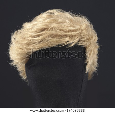 blonde feminine wig on black background and textile mannequin.