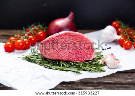 a pieces of fresh meat, beef slab, decorated with greens and vegetables
