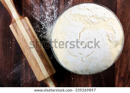 Freshly prepared dough on a wooden board. Rolling pin and flour.