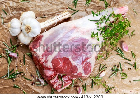 Raw lamb leg on crumpled paper background with herbs.