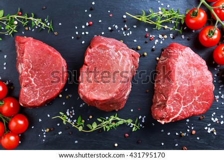 Fresh Raw Beef steak Mignon, with salt, peppercorns, thyme, tomatoes.