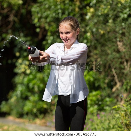 Wet teenage girl in white shirt and black legging squeezes water from plastic bottle.