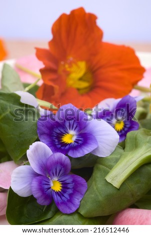 salad of edible flowers in ceramic dish. colorful summer dish. with nasturtiums, pansies, roses and mache.