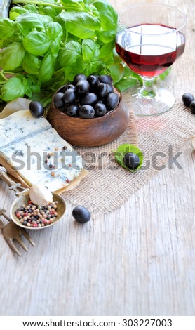food ingredients, cheese, olives, wine and basil on a wooden background, cooking concept