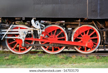 Three, red,very old locomotive wheels on tracks.