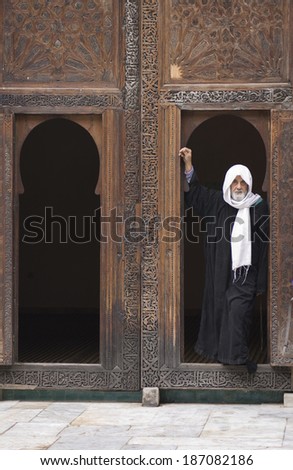 Rabat, Morocco - December, 21, 2009; Man with his head covered in decorated wooden doorway in Fez medina, Morocco