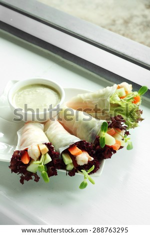 shrimp and vegetable vietnamese roll and white sauce in white ceramic dish