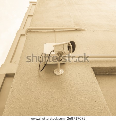 cctv camera install on the wall outside building with sepia color tone