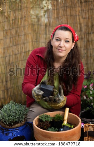 Woman gardening with different plants in front of a bamboo fence