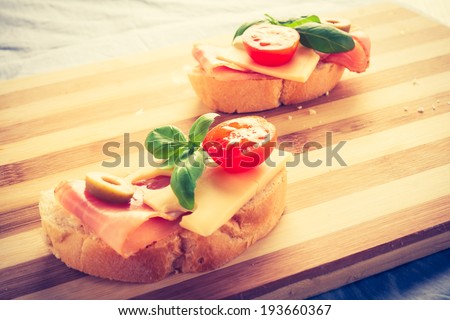 vintage photo of small sandwiches with smoked ham, cheese and cherry tomato