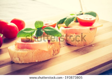 vintage photo of small sandwiches with smoked ham, cheese and cherry tomato