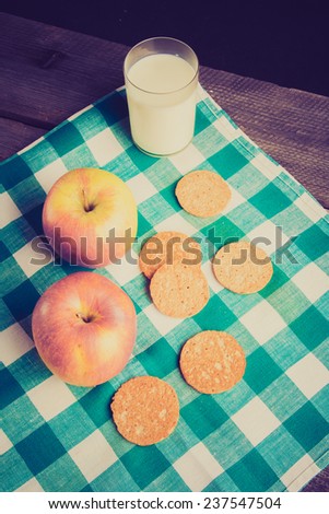 vintage photo of sweet cookies, glass of milk and apples