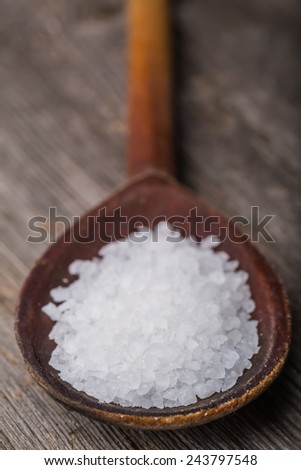 Old Brown wood spoon with salt crystals on wood table
