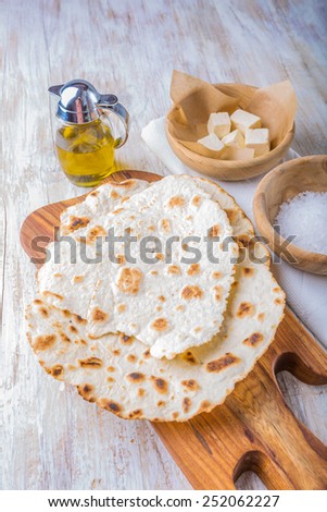 Fried tortilla with cheese on olive wood plate on white background