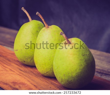 Vintage photo of pears on wooden cutting board and ancient wooden table