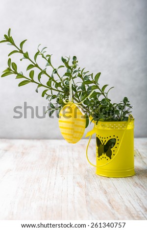 Easter decoration - yellow egg and buxus on a wood table