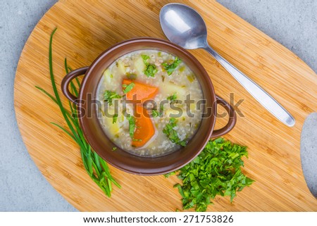 Traditional barley soup with parsley in a dark bowl