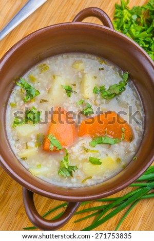 Traditional barley soup with parsley in a dark bowl