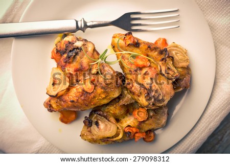 Vintage photo of oven-baked chicken wings with vegetables. studio shot