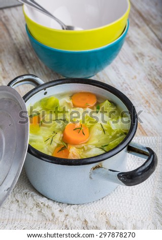 Fresh cabbage soup in a pot on white wooden table