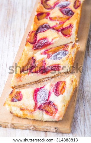 Cheesecake with plums on wooden table, studio shot